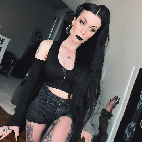 a towering 6ft tall single mom goth girl with long hair and sharp winged eyeliner, posing as an influencer for TikTok in a dark modern aesthetic